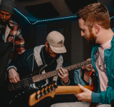 Un grupo de personas toca guitarra en un estudio de grabación en 2023.