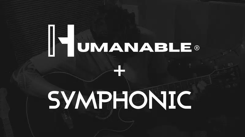 Un artista toca una guitarra acústica con las palabras "HUMANABLE + SYMPHONIC" sobrepuestas en letras blancas en negrita.