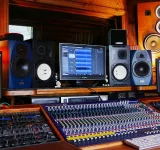 Una configuración profesional de estudio de grabación con varios monitores, consolas de mezcla de audio, altavoces y varios equipos de audio en una sala revestida de madera: ideal para artistas y sesiones de sello.