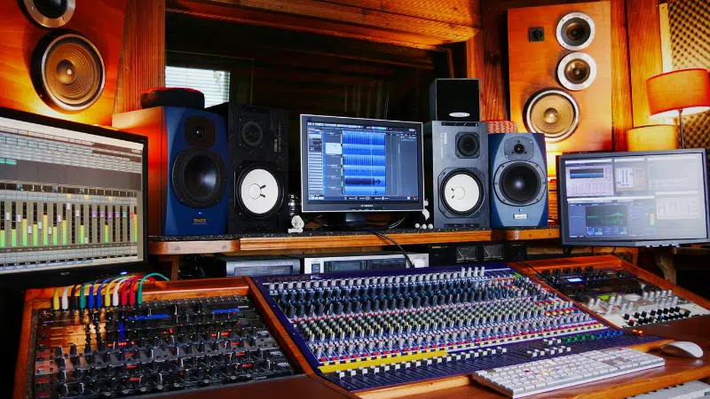 Una configuración profesional de estudio de grabación con varios monitores, consolas de mezcla de audio, altavoces y varios equipos de audio en una sala revestida de madera: ideal para artistas y sesiones de sello.