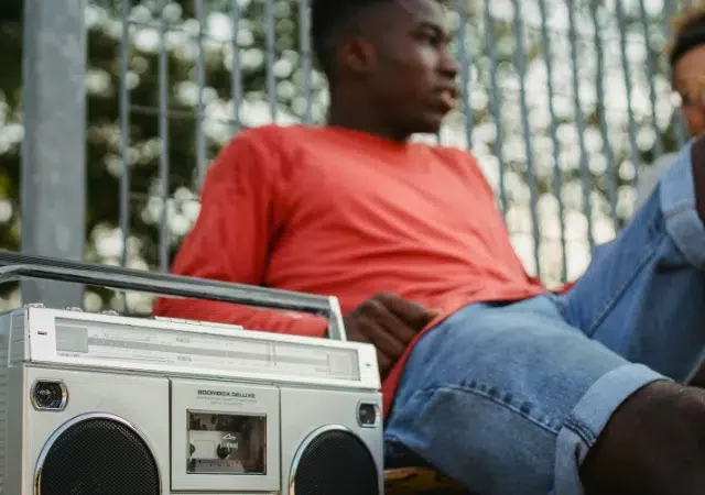 Una mujer con cabello largo y castaño y gafas sonríe a la cámara, lleva puesta una camisa blanca y está de pie frente a una puerta de madera.