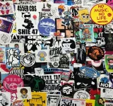 Una pared densamente cubierta de stickers coloridos variados, con diferentes personajes, logos, slogans de marcas registradas y diseños artísticos superpuestos entre sí.
