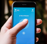 Una persona sostiene un smartphone que muestra la app de Shazam con el botón destacado “Tap to Shazam”, listo para el descubrimiento musical.