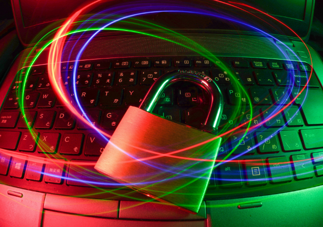 Un candado descansa sobre el teclado de un laptop con trazos de luz roja y azul girando, representando la ciberseguridad, la protección de datos y la seguridad del copyright en el mundo digital.