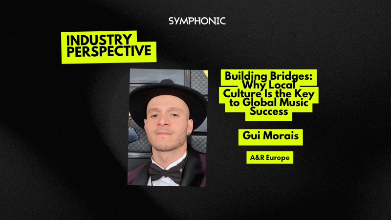 Una persona con un sombrero negro de ala ancha, corbatín y saco posa frente a un fondo con símbolos dorados de gramófonos.